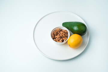 Dish with avocado, lemon and walnuts in a plate on a white background. Top view with space to copy. The concept of healthy eating.