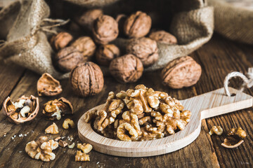 Fototapeta na wymiar Whole and peeled walnuts on a rustic wooden table, focus on the walnut kernels