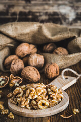 Whole and peeled walnuts on a rustic wooden table, focus on the walnut kernels, vertical