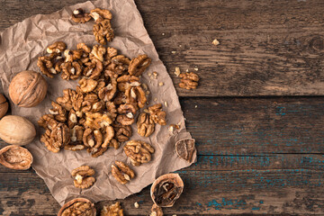 Walnuts peeled and whole on a paper napkin on a wooden background. Top view with space to copy. The concept of useful products.