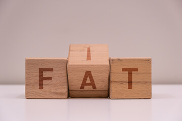 Change the word "fat" to "fit" with wooden letter cubes. Slimming or being overweight. Weight change demonstration. Motivation.