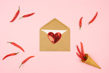 Red hot chilli peppers with a brown envelope with a red lie on a pink background table. Copy space.