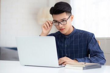 Young business man in glasses working from home with laptop computer on desk, freelance male sitting stay home using notebook for communication on table, entrepreneur in startup business, new normal.