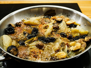 Pork steaks in frying pan with onion, garlic, plums  and champignons
