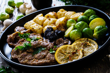 Fried pork steaks with lemon, dumplings and boiled brussels sprouts served on wooden table
