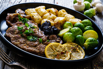 Fried pork steaks with lemon, dumplings and boiled brussels sprouts served on wooden table
