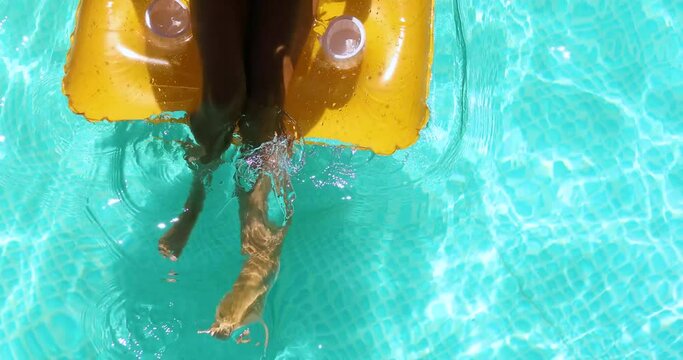 Little girl in sunglasses relaxing in swimming pool, enjoying suntans, swims on inflatable yellow mattress and has fun in water on family vacation, tropical holiday resort, view from above