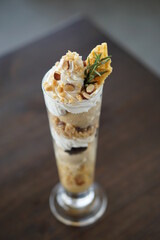 Angle top view of ice cream parfait with chocolate,coffee and nuts on black wood table.