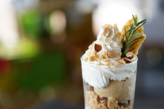 Close-up of ice cream parfait chocolate,coffee and nuts with Christmas tree bokeh background on black wood table.
