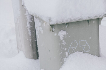 Recycling symbol in grey trash can in Madrid covered in snow due to Filomena storm.