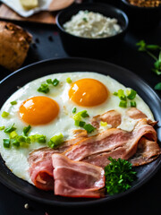 Continental breakfast - sunny side up eggs on bacon on wooden table