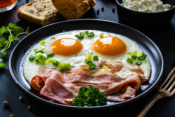 Continental breakfast - sunny side up eggs on bacon on wooden table
