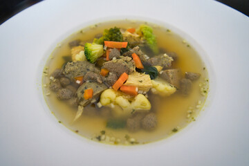 Ein weißer Teller Gemüsesuppe, Hühnersuppe mit Karotten, Leberknödel und Bio Gemüse, Hausrezept nach Oma in der Erkältungszeit