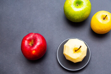 Apples green, yellow, red and apple without peel on a black background. Healthy food concept with copy space
