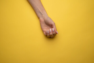 Female hands with a beautiful manicure on a yellow background,top view