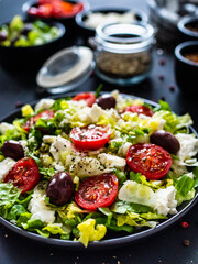 Fresh Greek salad - feta cheese, tomatoes, cucumber, lettuce, black olives and onion on wooden table