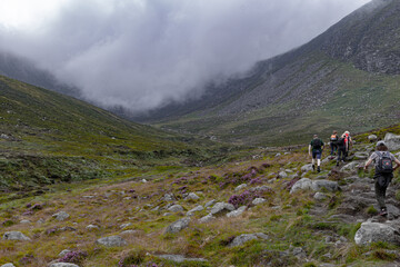 Fototapeta na wymiar Tourists on a hike walking on turistic trail in the mountains of Northen Ireland.