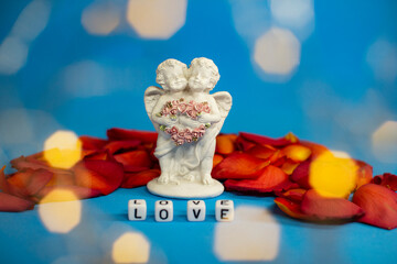 Two cute angels and the word love on the background of rose petals .Valentine's Day. Postcard for the holidays