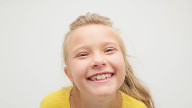 The girl is having fun and dancing on a white background in the studio in a yellow T-shirt.