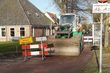 Wheel bulldozer with bucket at street in the Dutch village of Bergen during construction of the...