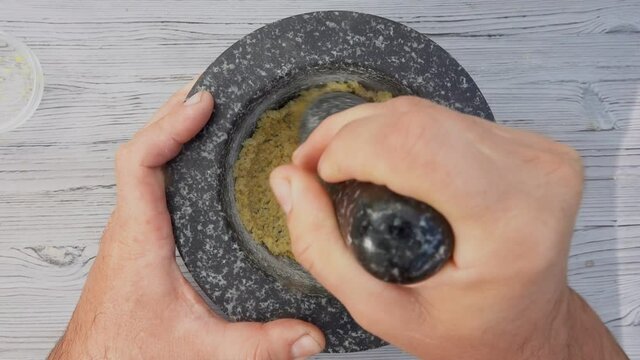 Male hands are grinding sea salt, lemon and brown sugar in the mortar with a pestle