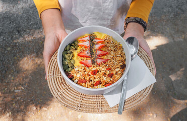 Top view woman holding a pineapple and mango smoothie bowls with fruits, fresh Strawberry, nuts, seeds and homemade granola for healthy vegan