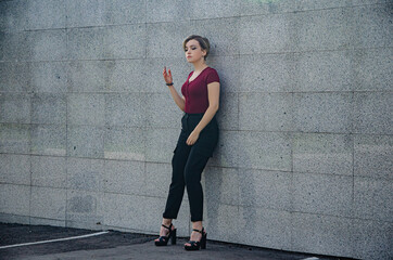 Fototapeta premium A girl stands on the street against a background of brick tiles