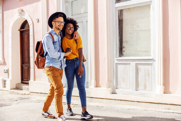 Young attractive multiracial couple in love walking outdoors and enjoying beautiful sunny day.