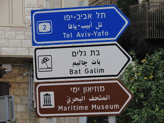 Road signs with the inscriptions Tel Aviv-Yafo, Bat Galim beach, and the Maritime Museum in three languages (English, Arabic, and Hebrew) close-up in Haifa, Israel.