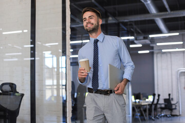 Young handsome businessman smiling in an office environment.