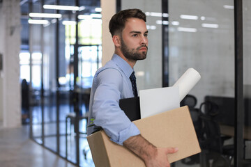 Fototapeta premium Sad dismissed worker is taking his office supplies with him from office.