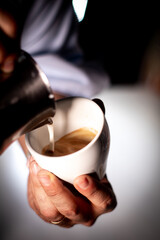 Detail of a man's hands serving a cup of coffee The milk has a nice shape.