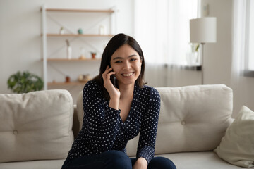 Happy beautiful asian korean mixed race woman involved in pleasant smartphone call conversation with friends sharing discussing life news, smiling female client calling operator ordering delivery food