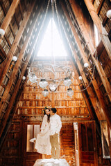 Young couple is standing on the table inside cozy wooden building
