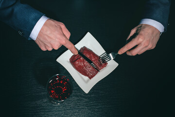 Supper of blue blood aristocrat. Portrait of handsome,young man eating fresh meat . Classical suit.  Luxury style. Indoor shot - Image