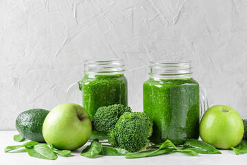 Green healthy detox smoothie with fresh vegetables and fruits in jars on white background. Healthy...