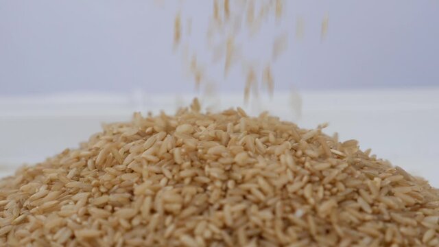 Clip of sprinkling brown rice over heap of brown rice