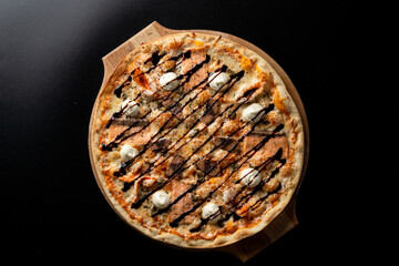 Smoked salmon pizza with small mozzarella balls, top view on black background