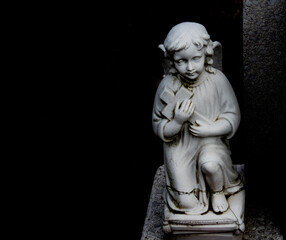 Stone statue of a child with a cross at the cementery