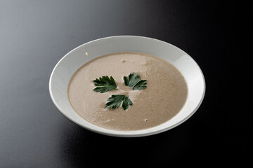 Minimalist and stylish photo for a restaurant menu: creamy mushroom soup with herbs
