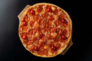Top view of hot pepperoni pizza on black background, copy space