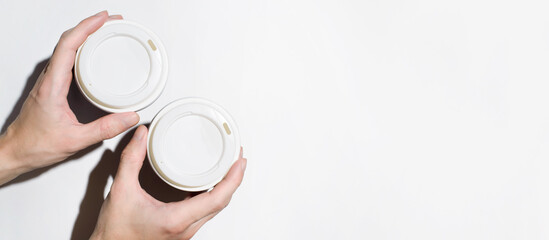 Male hands holding disposable cups with coffee on a white background, top view. Banner, copy space. Food delivery concept, coffee to go