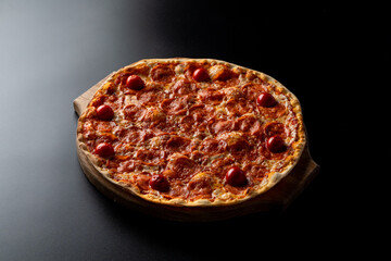 Hot oven-made pepperoni pizza with ,melted mozzarella cheese on smooth black background