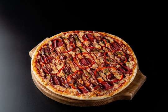 Side view of pizza with spanish sausages and hot chili sauce, ad photo