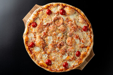 Mediterranean shrimp pizza with melted cheese, single object on a black background