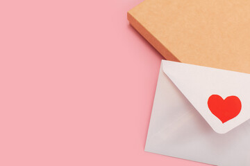 light mother-of-pearl paper envelope with red heart on the gift box isolated on pink background