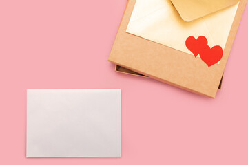 closed gift box and two paper hearts on it isolated on pink background