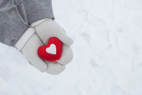 hands in white knitted gloves hold a red heart - a symbol of love and happiness, February 14 Valentine's Day