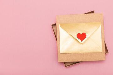 golden color paper envelope with red heart on the gift box isolated on pink background