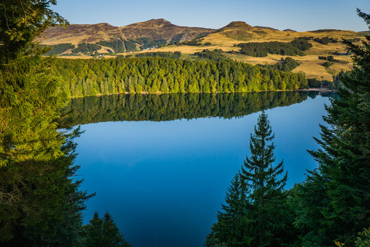 View of Lac Pavin in Auvergne (France), early in the morning. The Puy de Sancy volcano can be seen in the background